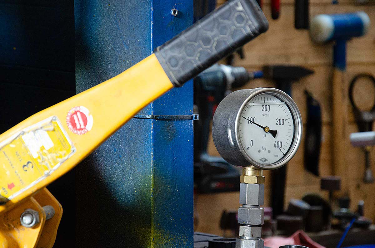 Druckmanometer mit Skala bis 400 bar in einer Werkstatt neben einem gelben Hebelarm.
