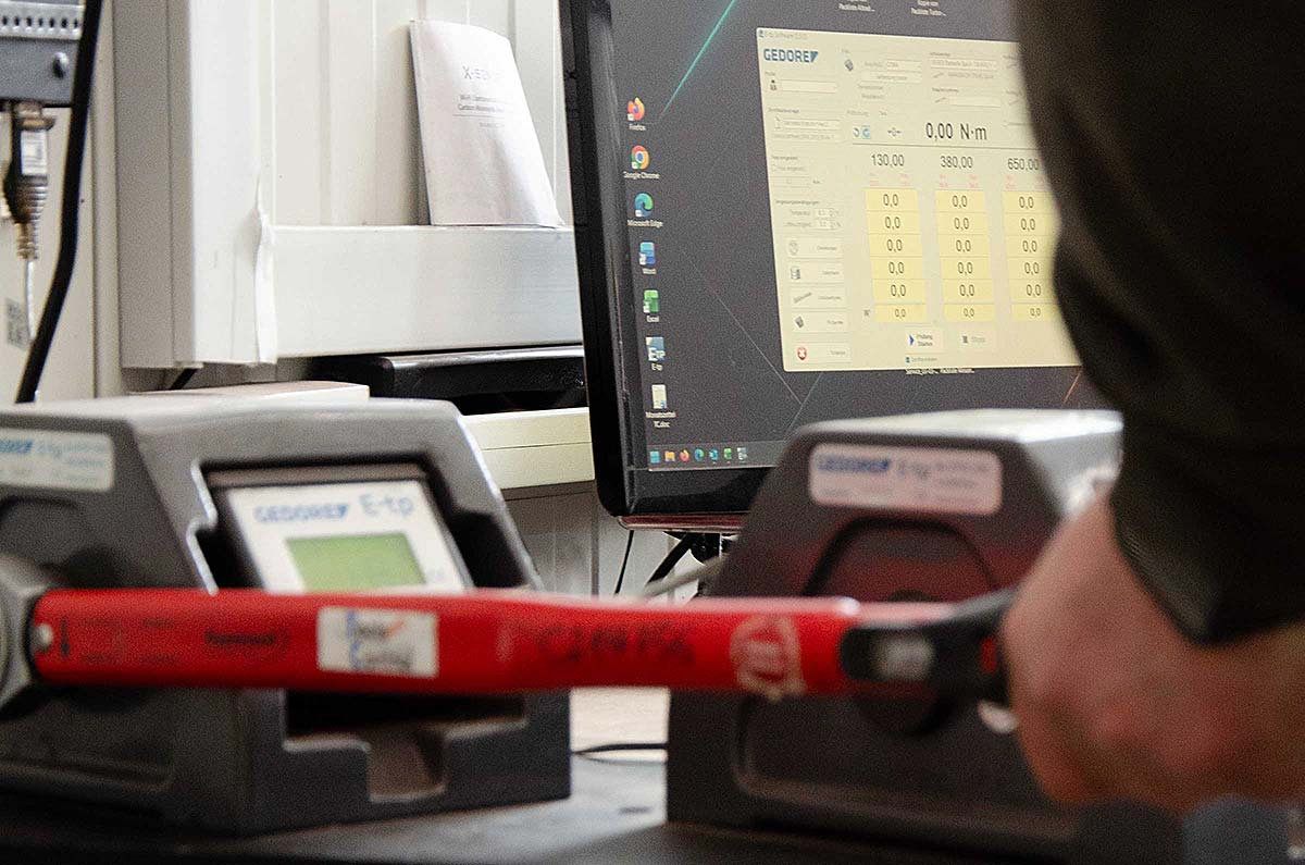 Person bedient ein digitales Drehmomentschlüssel-Messgerät vor einem Computerbildschirm mit Gedore-Software.