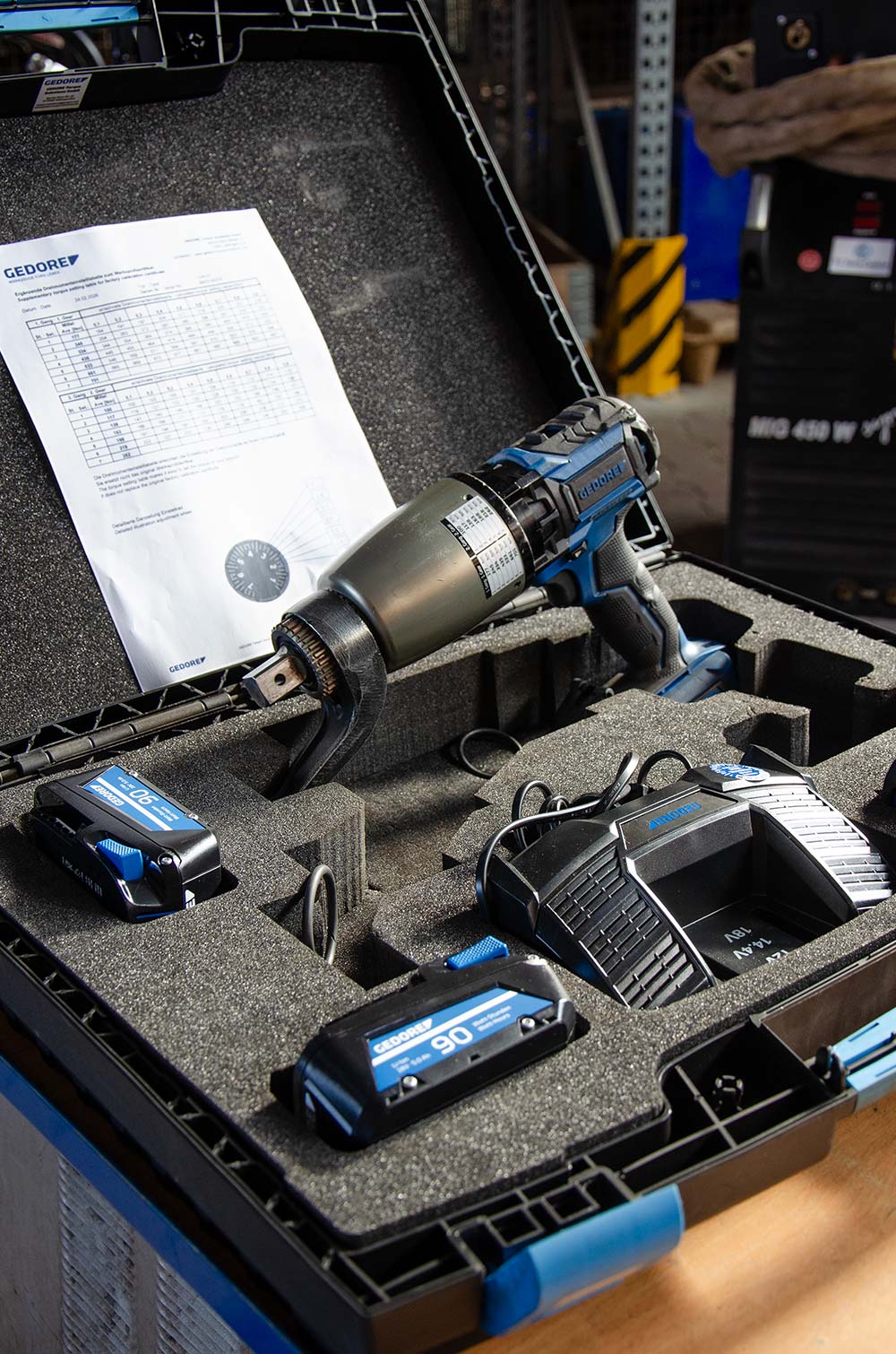 Werkzeugkoffer mit einem blauen, akkubetriebenen Drehmomentschlüssel von Gedore, Ladegerät und zwei Akkus.